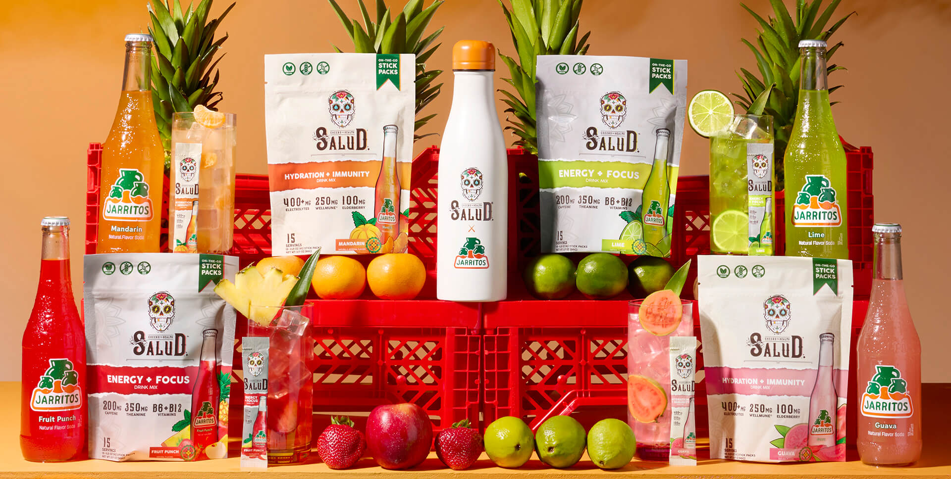 A vibrant product display highlights the collaboration between Salud and Jarritos, featuring Jarritos sodas and Salud’s vitamin-packed drink mixes in flavors like Mandarin, Lime, Fruit Punch, and Guava. Surrounded by fresh fruit and tropical visuals, the scene promotes wellness, hydration, and bold Latino flavor fusion.